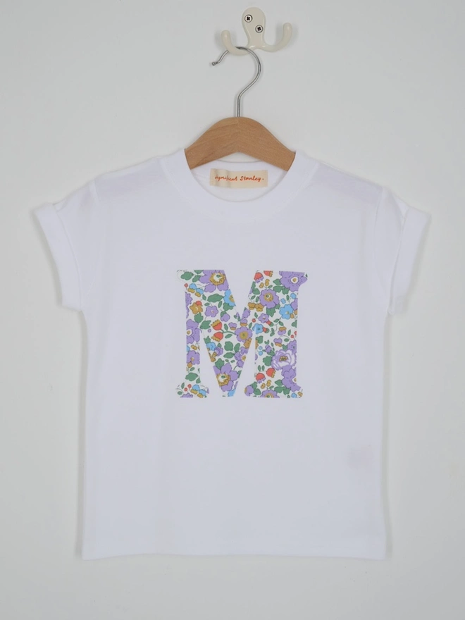 a personalised kids white t-shirt with an initial cut from betsy purple liberty floral print on the front