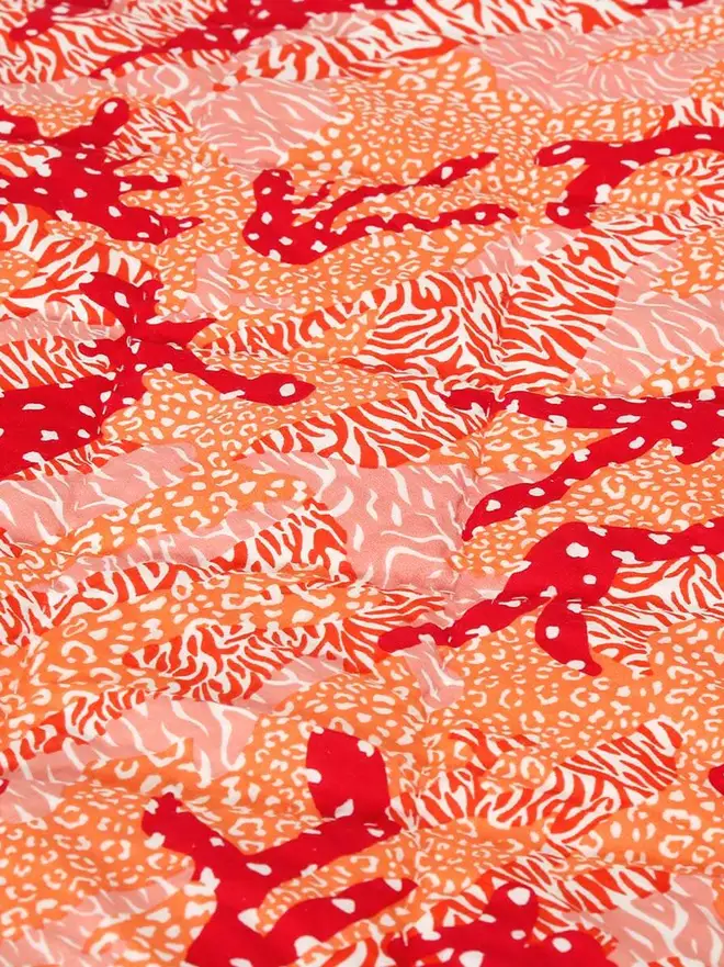 Big Cat Camo Quilt, a pink and green quilt on a bed in a bedroom. 