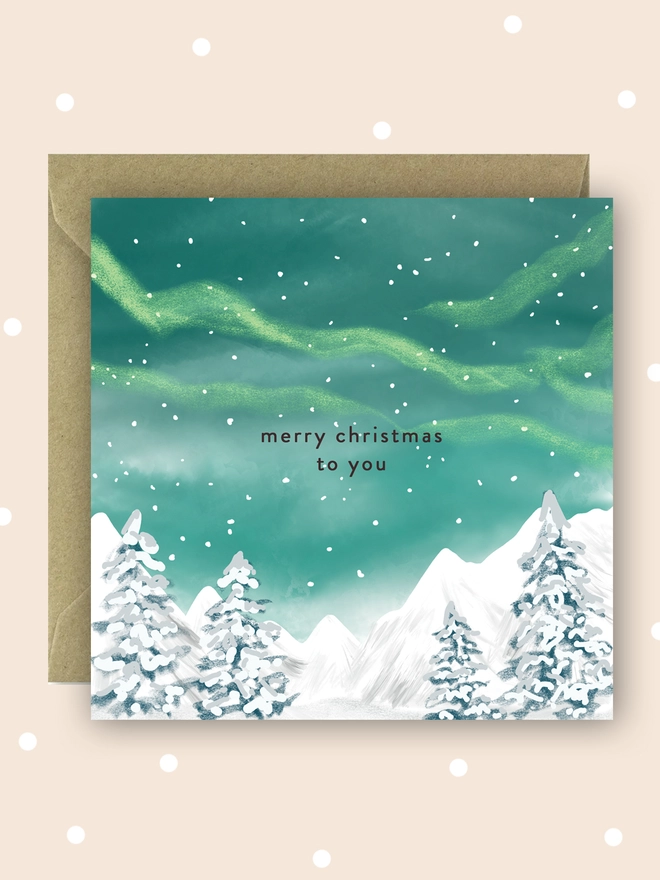 Merry Christmas to you card with a green starry sky over snowy trees and mountains