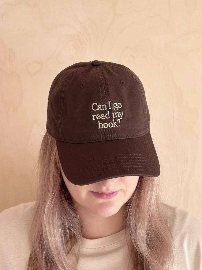 'Can I Go Read My Book?' Cotton Baseball Cap in brown being worn by a woman