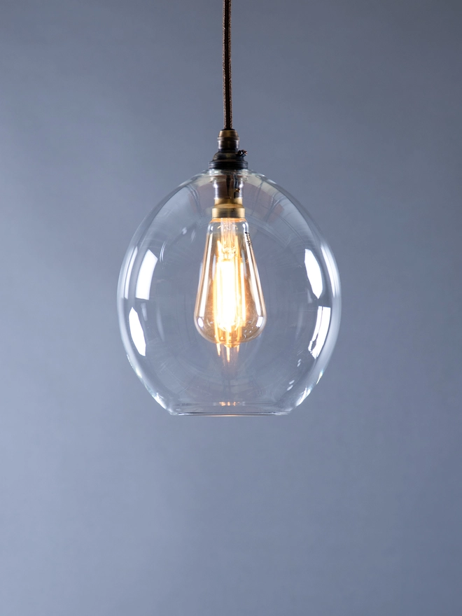Small Size Clear glass Wanda Pendant Light. Hand blown in Britain. Light is switched on 