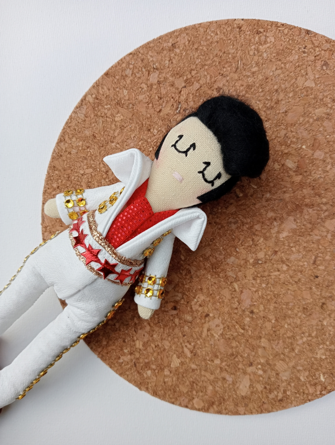 Mini decorative Elvis Presley icon doll shown on a round cork mat against a white background 
