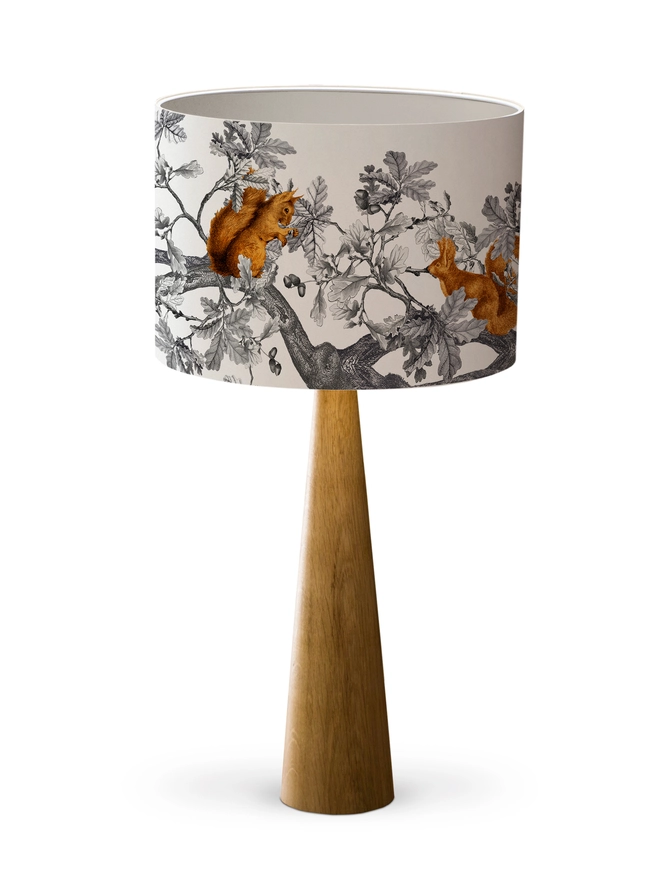 A decorative lampshade featuring red squirrels among oak leaves and acorns, inspired by the British countryside and woodland wildlife.