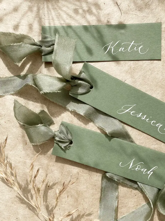 sage green calligraphy wedding place cards. green wedding place cards with silk ribbon and white calligraphy.