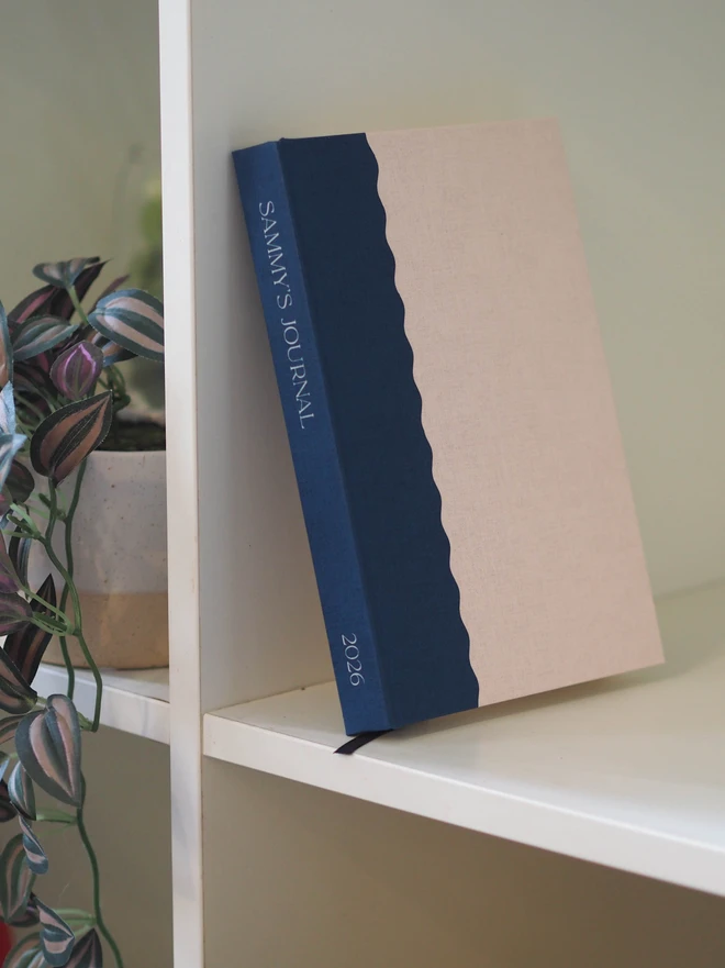 personalised notebook in a linen textured cover paper in a two tone scallop design with white personalised text down the spine