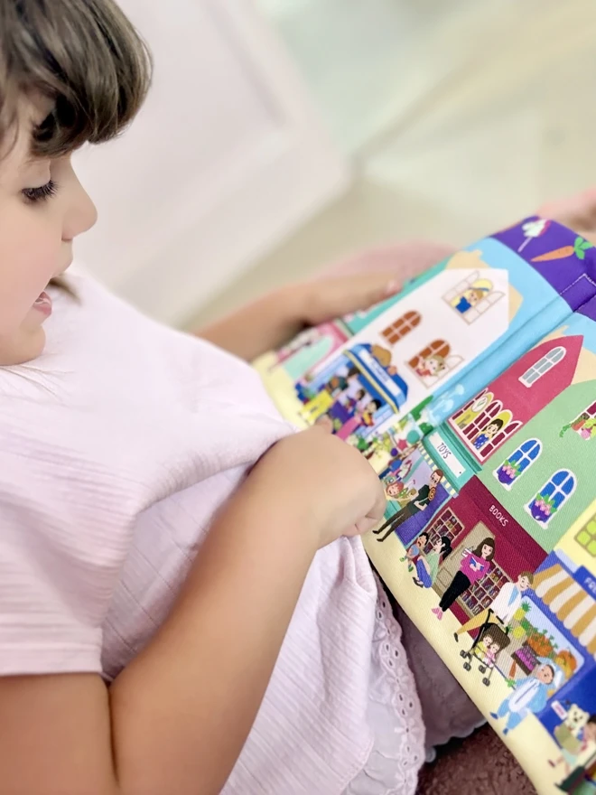 Girl pointing at house on Can you find Teddy? Search and find soft book