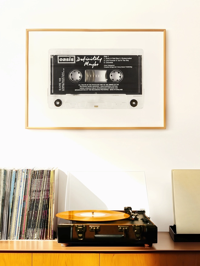 oasis definitely maybe cassette tape print. framed print hung up above record player and vinyl collection.