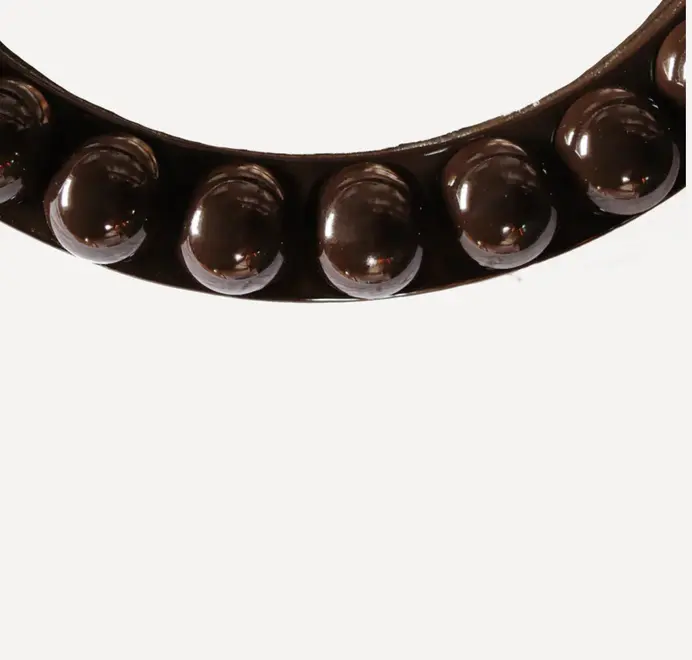 Round oversized bobbin mirror with a decorative bobbin-style wooden frame, hanging on a white wall.