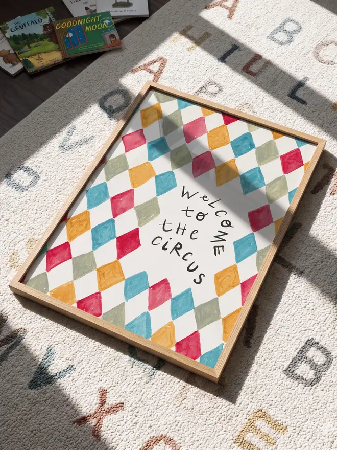 'welcome to the circus' art print. a print with a colourful diamond pattern background and a slogan in black letters. 