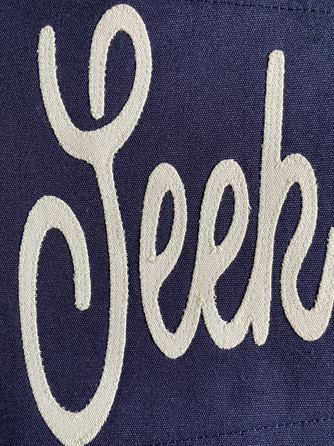 Detail of a nay 'Seek Adventure' pennant flag showing the won seek in ivory canvas