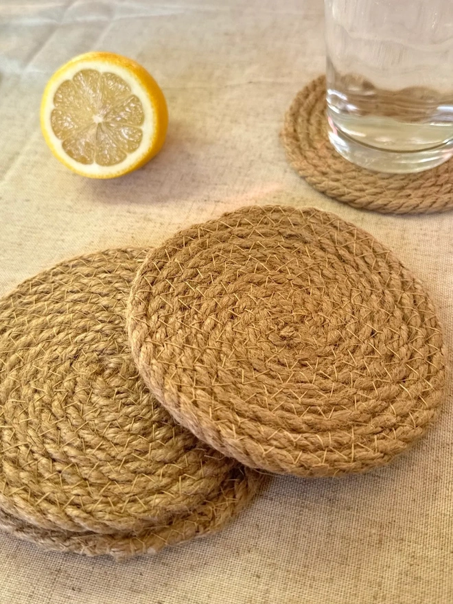 Seagrass coaster, shown on a light surface with half a lemon and cup of water. 