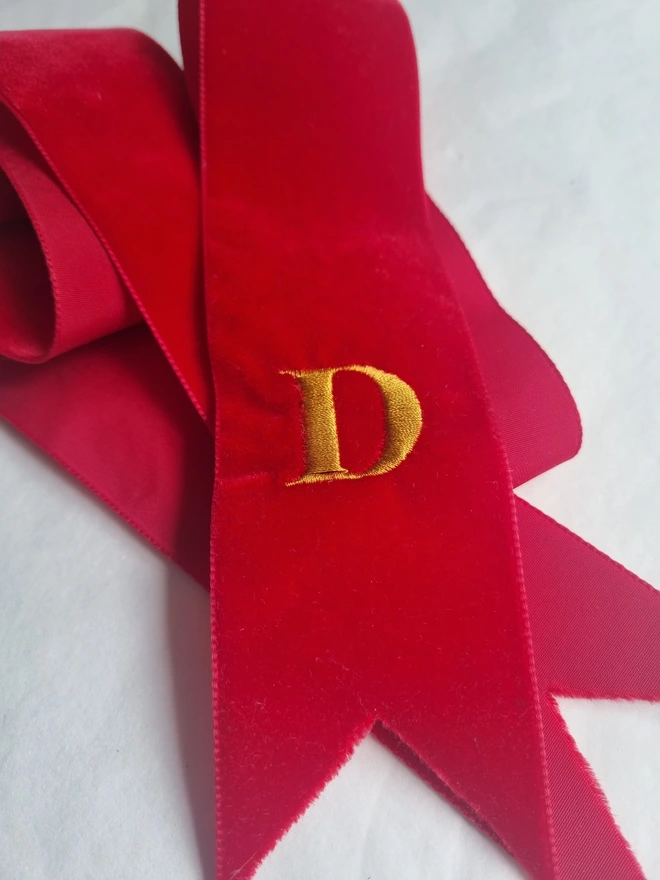 A red velvet ribbon embroidered with a D 