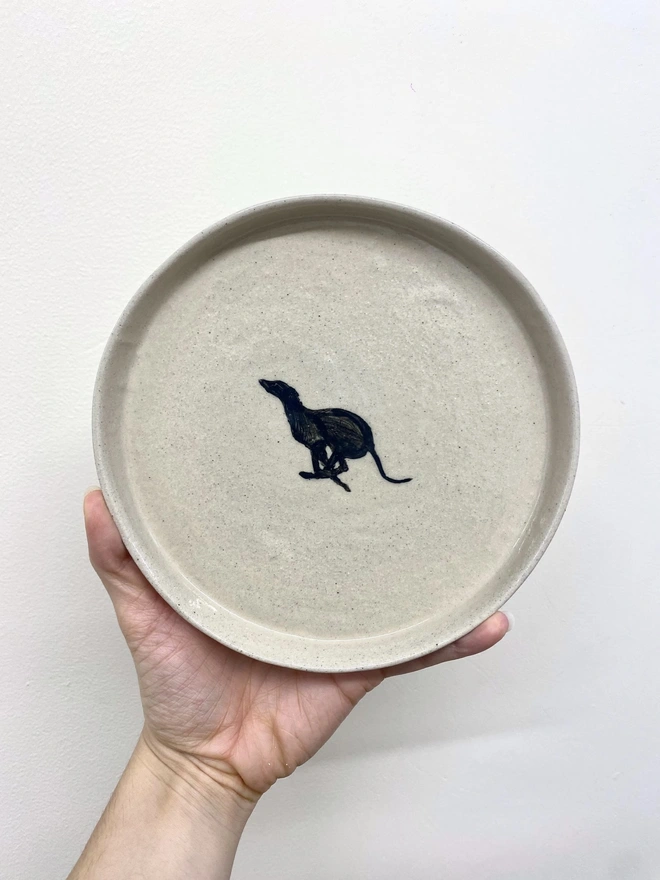 Handmade Ceramic Side Plate With A Black Greyhound Design, a person holding a ceramic side plate with a black greyhound design against a white backdrop. 