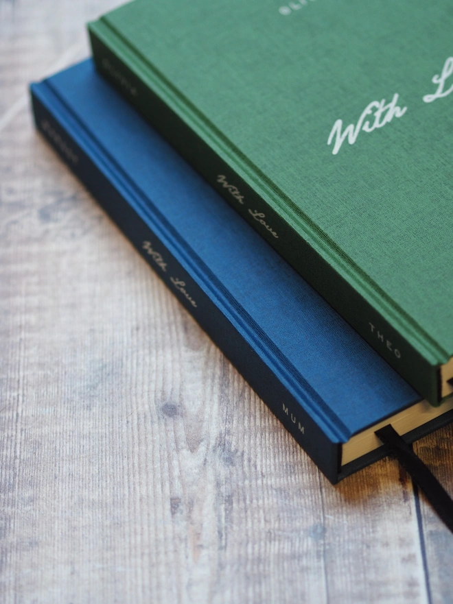 Personalised Hardcover With Love Notebook. A green and navy linen hardcover journal with the words With Love written across the middle in a script font in white ink. 