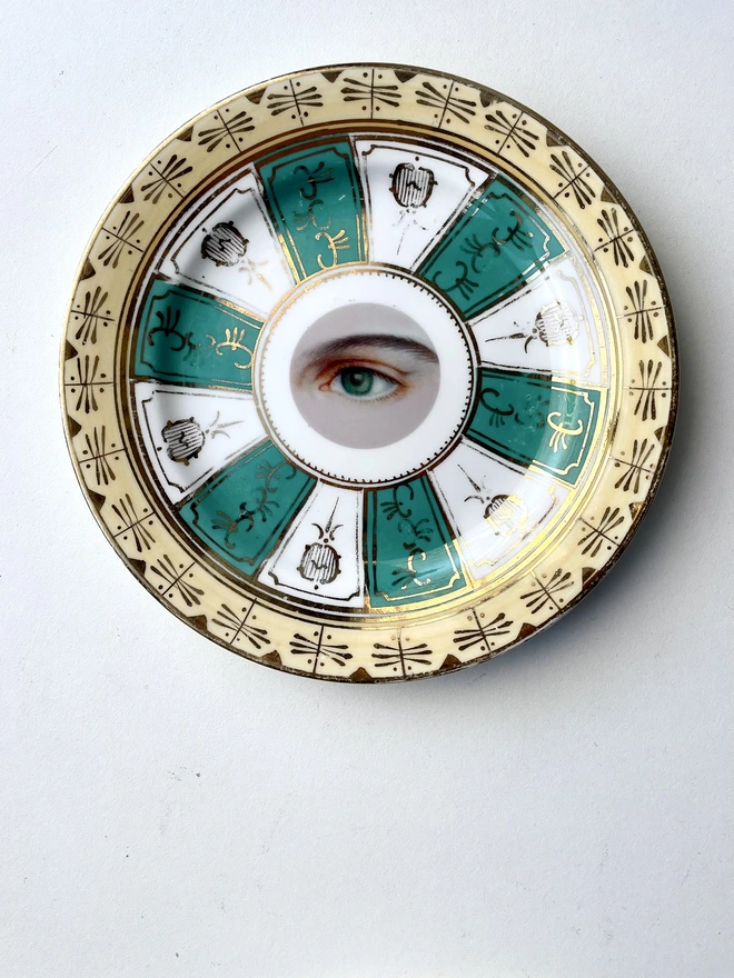 vintage plate with an ornate border, with a printed vintage illustration of an eye in the middle