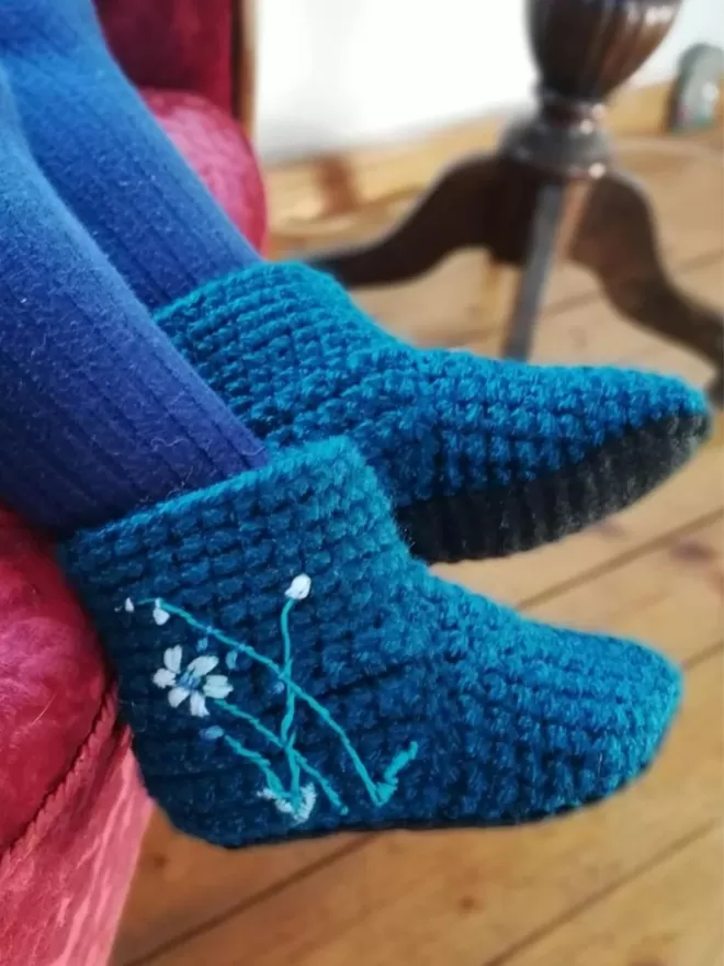 EKA blue crotched with embroidered flowers seen on a child seated on a sofa.