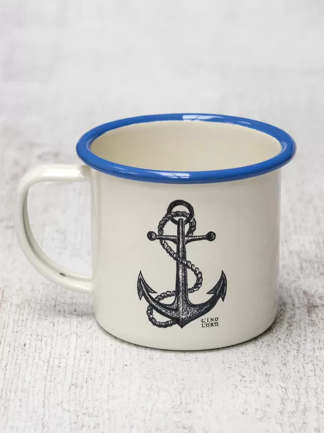 Picture of a Cream Enamel Mug with a Blue Rim with a Anchor design etched onto it, taken from an original Lino Print