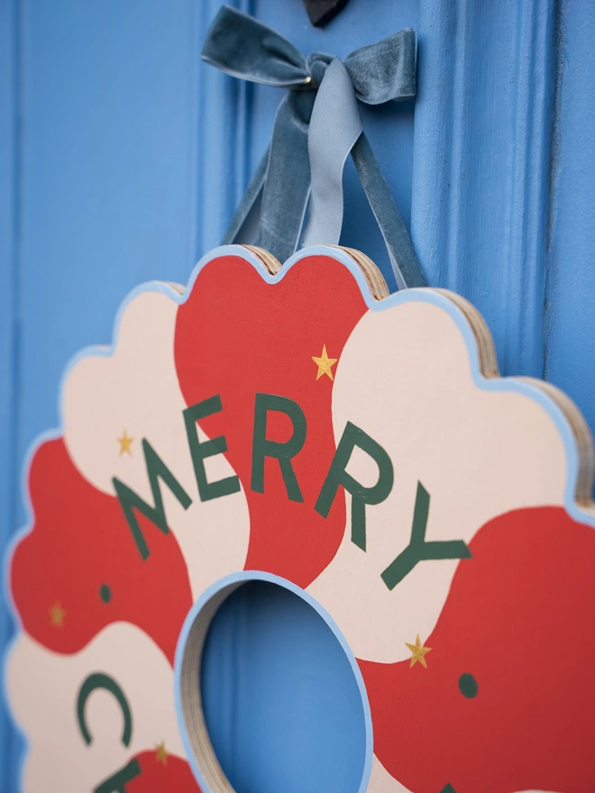 Red and pale pink Hand painted Christmas Wreath with gold leaf stars on a blue front door