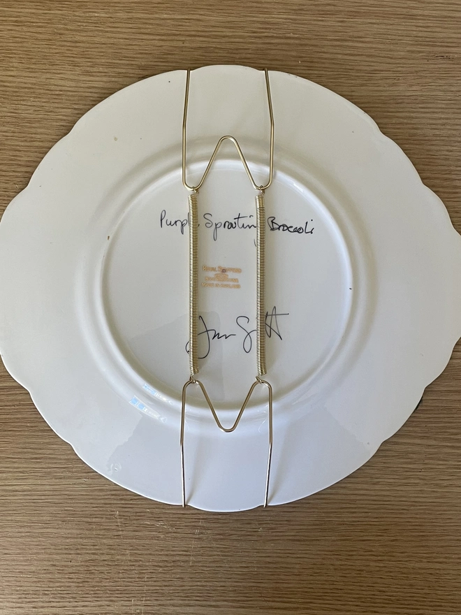 back of plate showing painting title and plate hanger