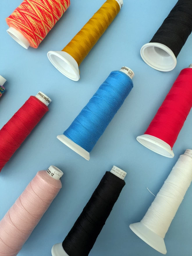 A selection of embroidery thread colour-ways on a blue background