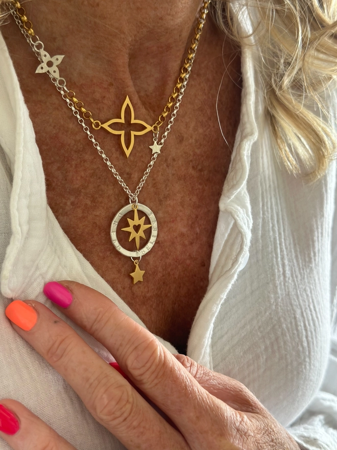 model wears a sterling silver chain with personalised silver halo charm. suspended within the halo is a gold starburst charm with cutout heart, with gold mini star suspended from the bottom of the halo