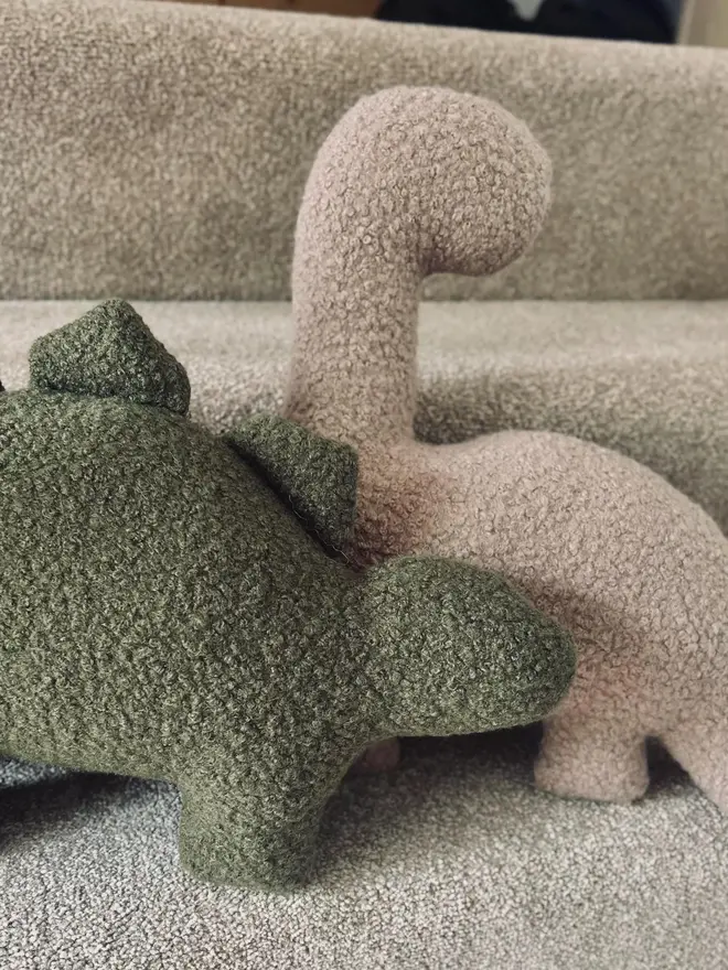 boucle dinosaur pillows. a green stegosaurus and beige diplodocus cushion.