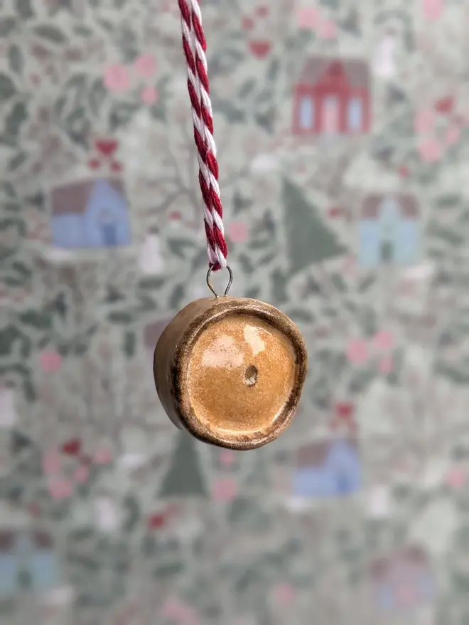 ceramic scotch pie hanging christmas decoration. a small ceramic pie decoration hanging from red and white string.