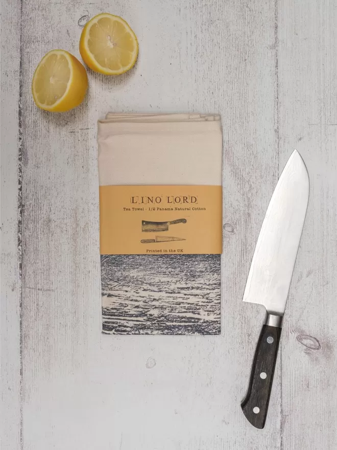 Picture of a tea towel with an image of a knife and a cleaver, taken from an original lino print