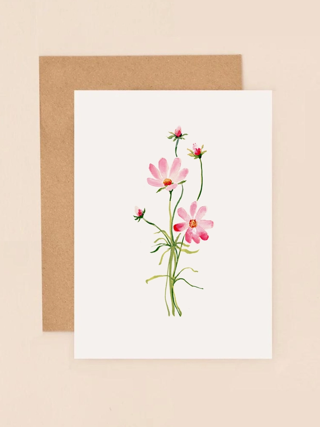 A delicate illustration of a single cosmos flower with soft pink petals and a yellow center, set against a muted background. The flower's gentle curves and fine details capture its natural beauty. The card is left blank inside, providing space for a personal message. Printed on thick, textured FSC-certified board, this eco-friendly mini card measures 90mm x 120mm, making it a charming choice for various occasions.