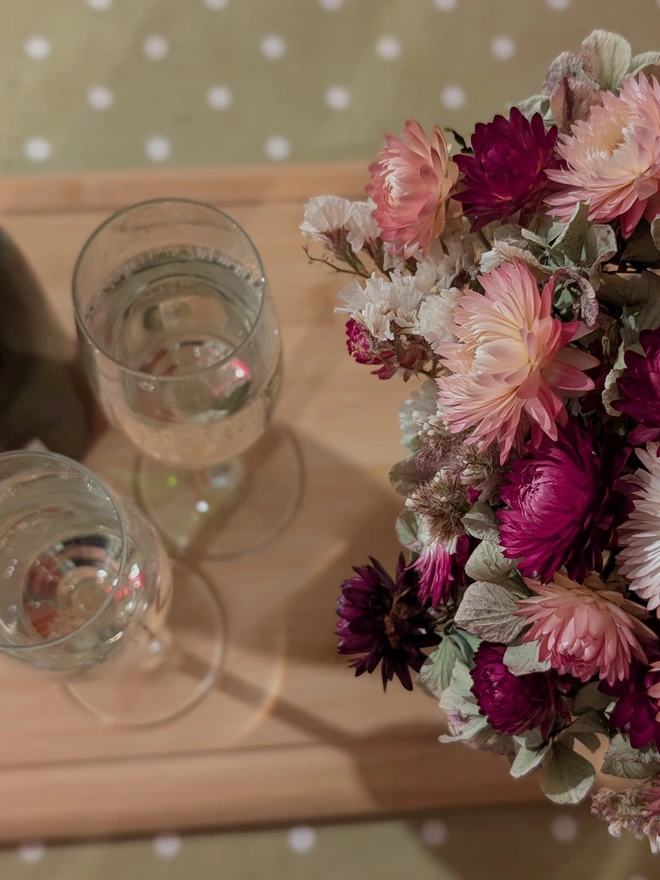 Bunch of pink flowers on table with champagne glasses