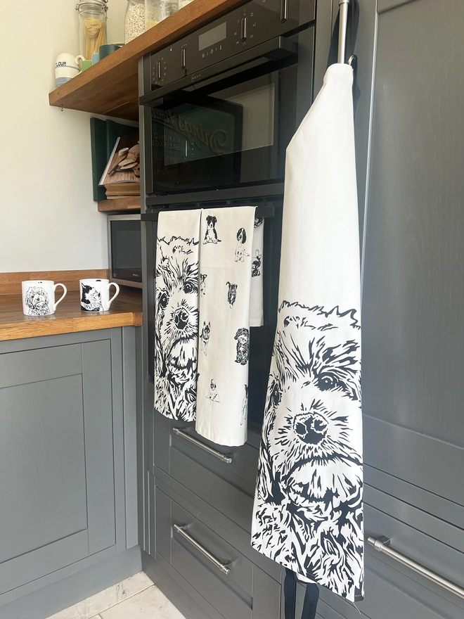 Cockapoo apron hanging from oven door, next to fold matching tea towel and mug