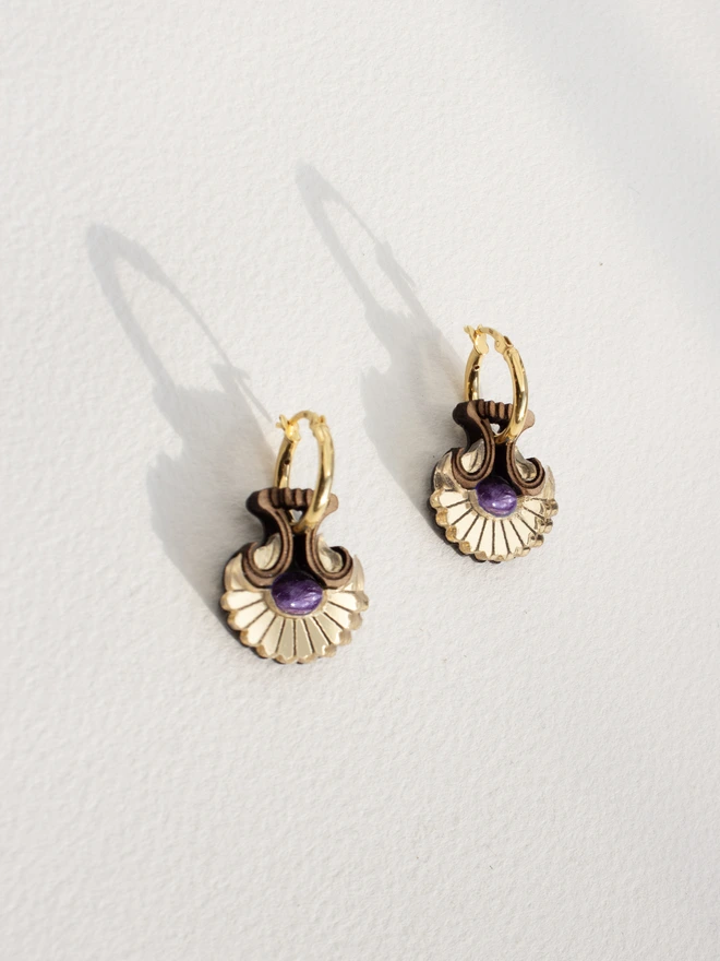 Pair of gold hoop earrings with natural stones on a light gray background