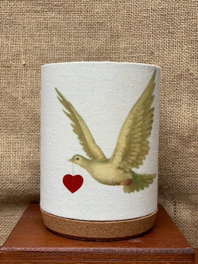 Hand printed fabric shade for a candle, with a dove carrying a heart