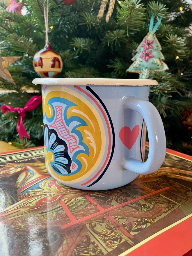 Blue enamel jug hand painted with a fairground design in blue, pink and yellow