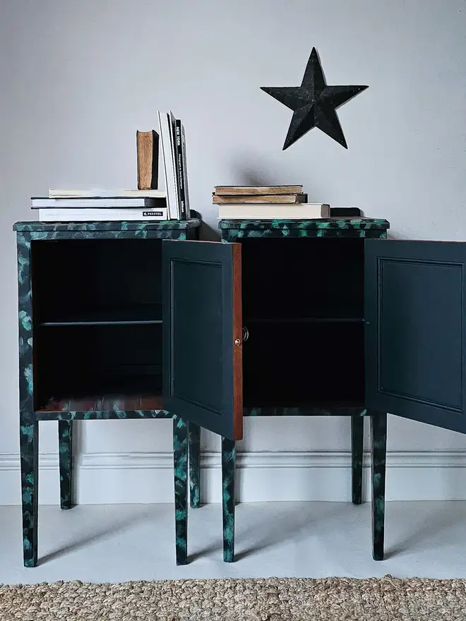 Interior of dark green bedside cabinets with the doors opened to reveal matching green interior, the edge of the doors have been left natural mahogany to add character and there is just a glimpse of leopard print pattern on the edges and where the legs are shown.