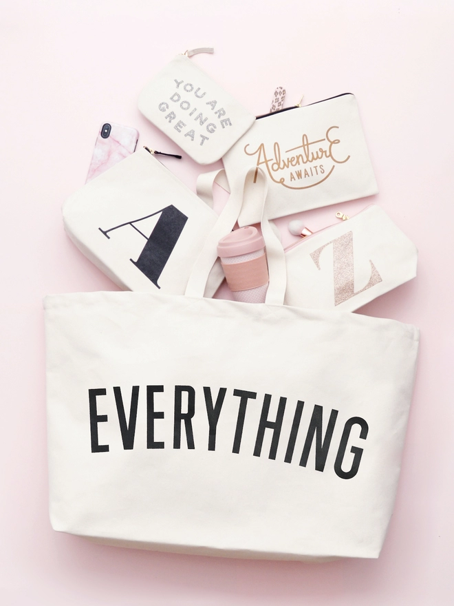 Everything oversized tote bag in natural canvas on pink background with canvas pouches spilling out