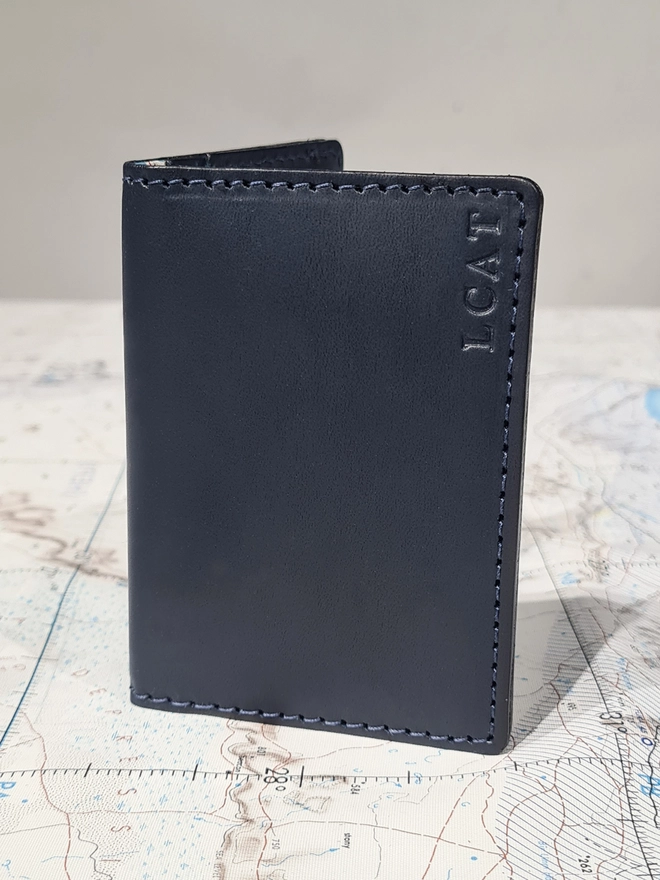 a navy blue leather card holder lined with a rare original escape map from the war by Natthakur