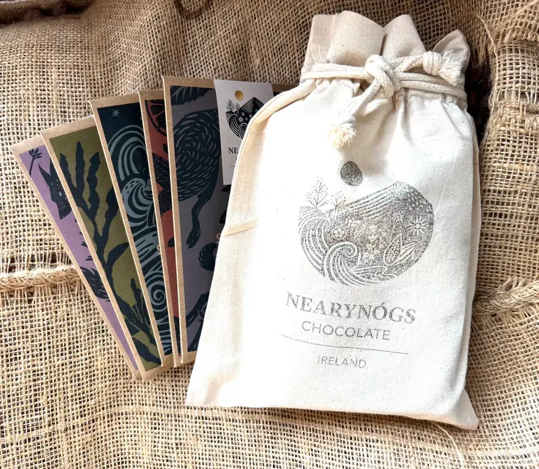 Irish Collection Chocolate Bars (Set Of 5), a collection of chocolate bars sitting on a fabric surface. They are accompanied by their packaging. 