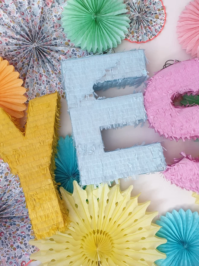 pastel letters spelling out the word YES surrounded by pastel and patterned paper fans