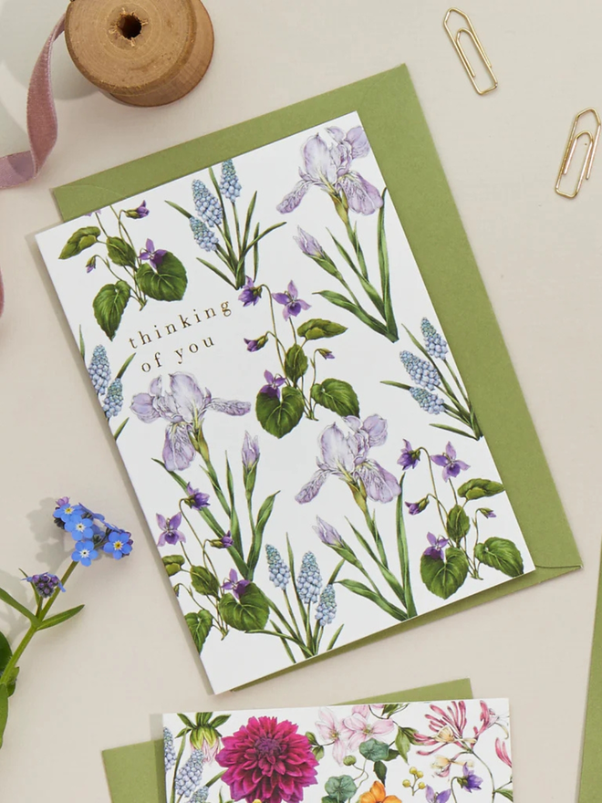 'thinking of you' illustrated floral card. a white floral card and green envelope photographed against a white background.