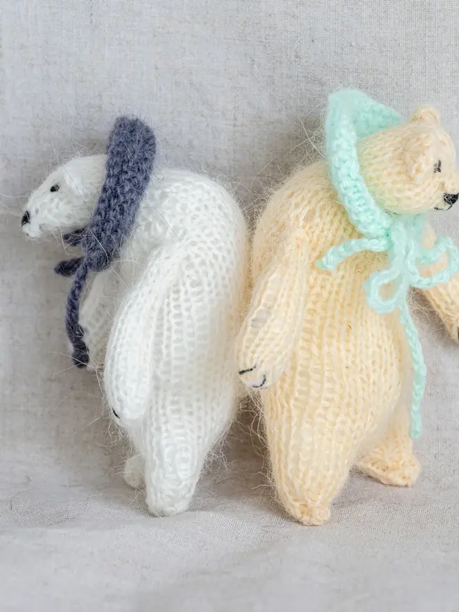 Ottilie The Bear Cashmere Figure, a pair of cashmere bears held by a person against a grey backdrop. 