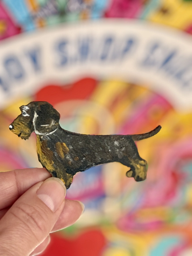 Wire Haired Dachshund wooden hand-painted pin  badge held up on a colourful  background