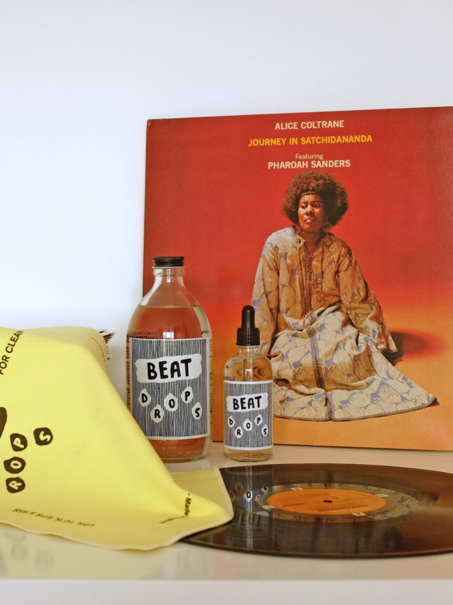 Beat Drops Record Cleaner. Two bottles of record cleaner set in front of a record and cleaning cloth.