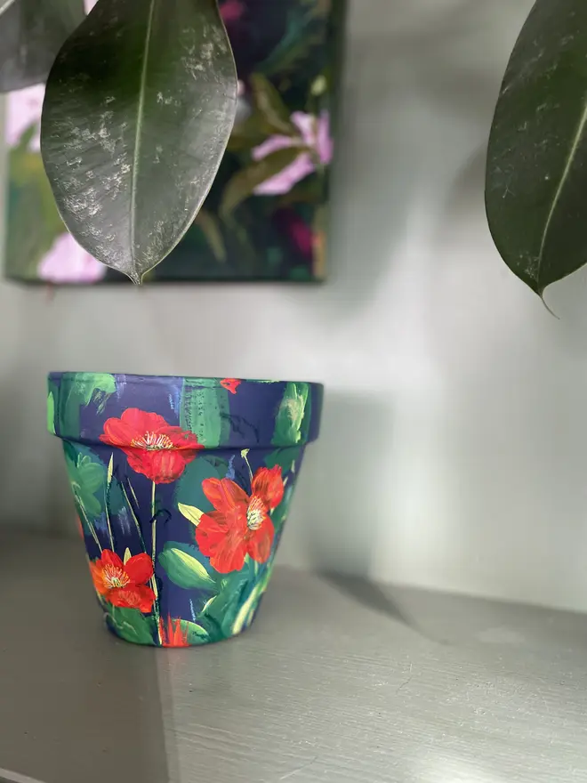 hand painted terracotta floral plant pot rich dark blue background with red orange Icelandic poppy flowers 