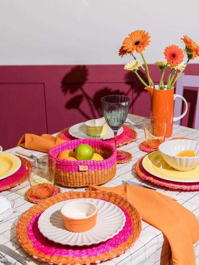 table setting using pink and orange woven tableware