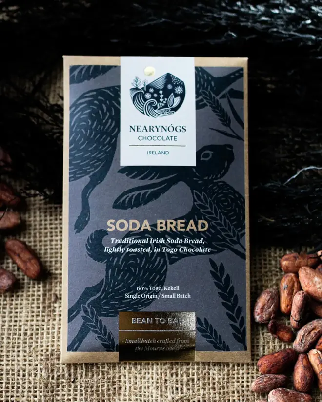 Irish Soda Bread Chocolate Bar, a chocolate bar sitting on a fabric surface accompanied by some nuts. 