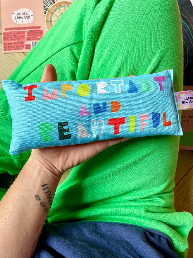 Brightly coloured lavender eye pillow held against green trousers