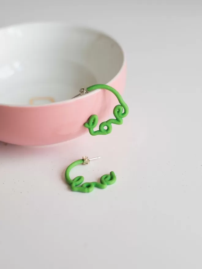 Small green love hoops seen in a pink cup.