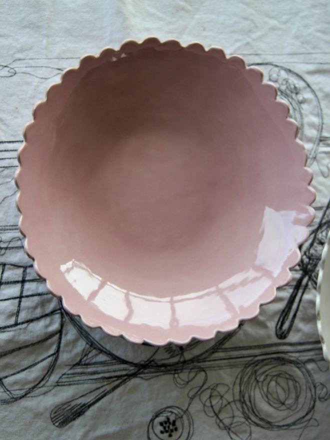 looking into the bowl of a scalloped handmade bowl in pink