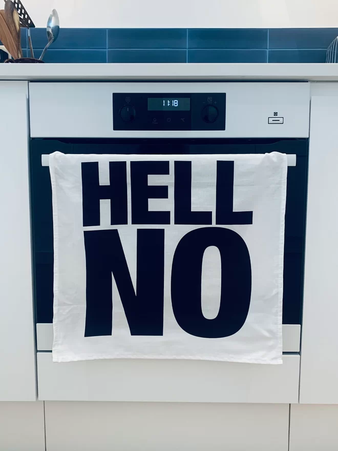 Hell Yeah Hell No black screen printed text on white tea towel hanging over oven handle with Hell No only facing